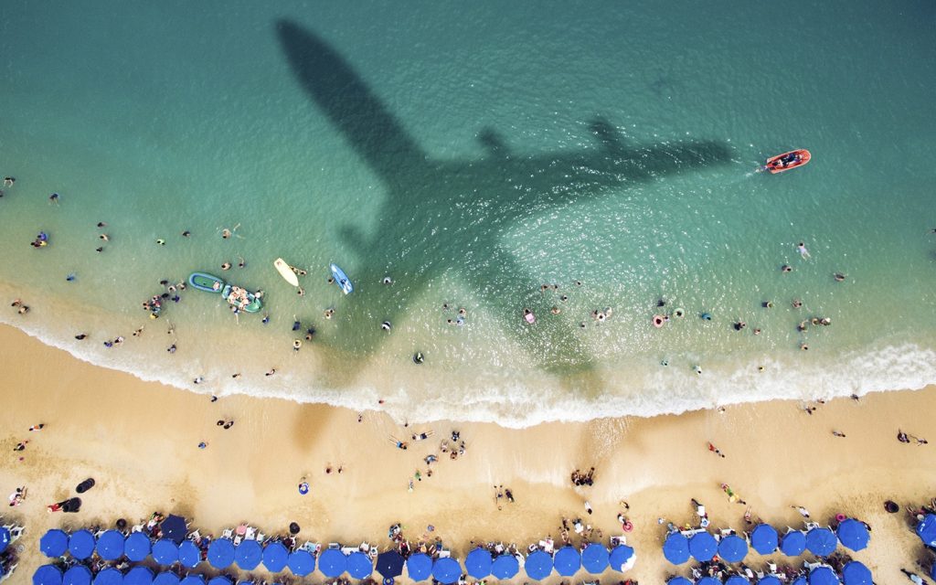 Airplane's shadow over a crowded beach