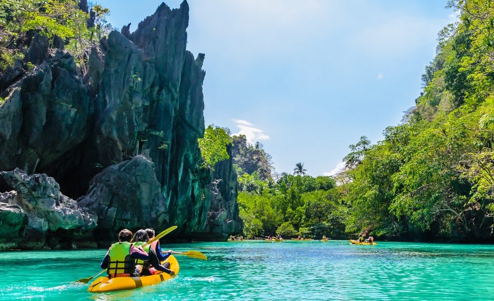 Kayaks in the big lagoon with turquoise clean water, tropical forest , rocks,,  El Nido, Palawan, Philippines